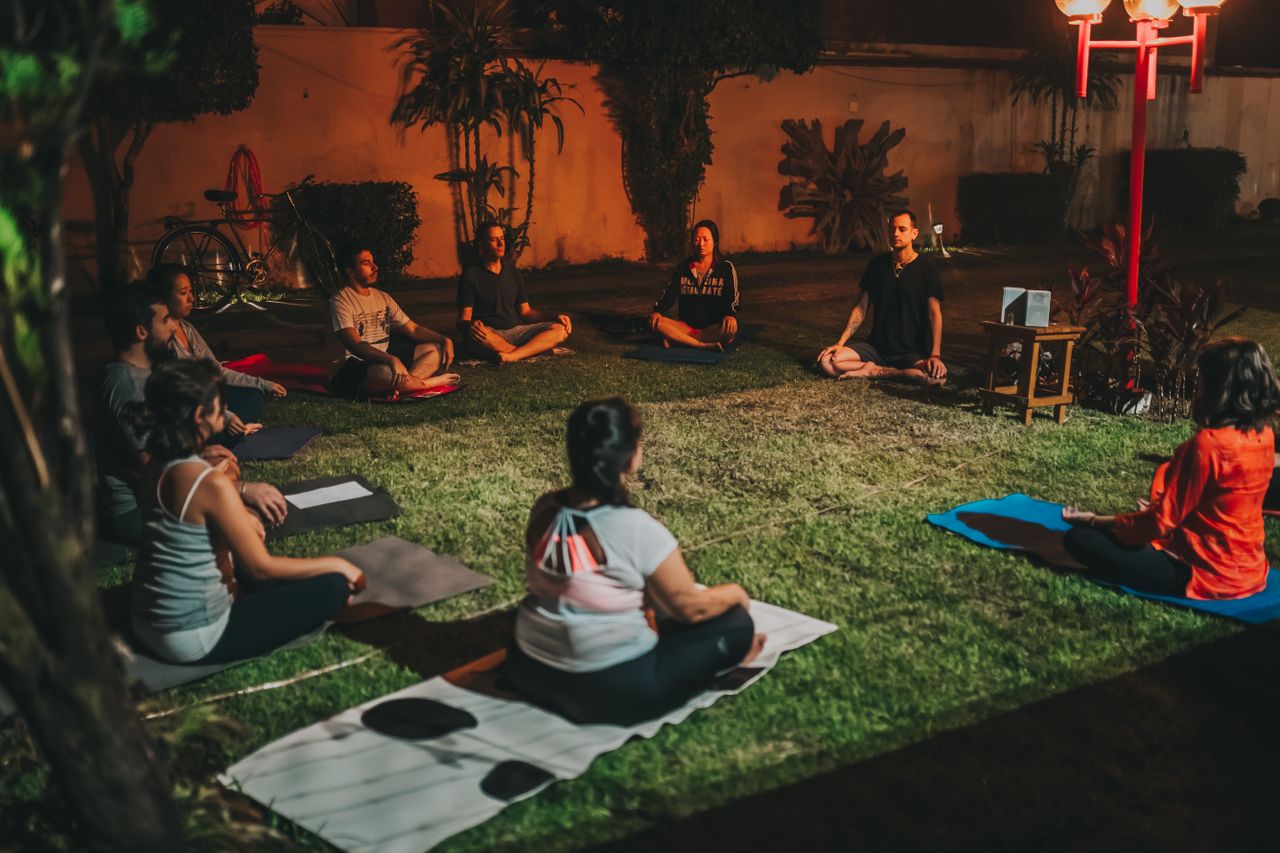 social-feed-img-03 Group practicing yoga outdoors at night for relaxation and wellness.