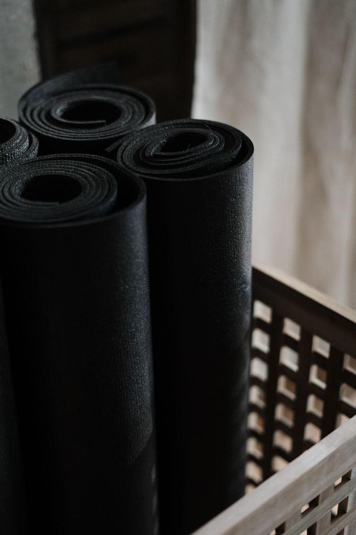 Crafting Captivating Headlines: Your awesome post title goes here Close-up view of black yoga mats rolled and stacked in a wooden basket indoors.