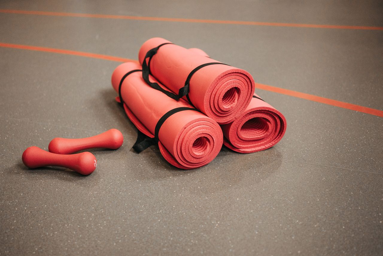About Red exercise mats and dumbbells on a gym floor, perfect for home or studio fitness.